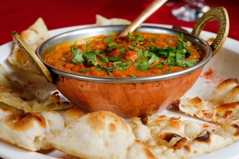 Indian curry in a copper dish with naan bread