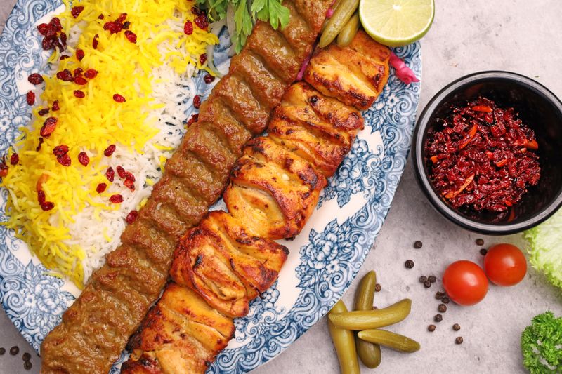 Persian kebab on saffron rice with grilled tomatoes and herbs